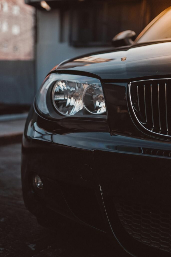 Steely close-up of a modern luxury car highlighting its sleek headlights and shiny bumper.